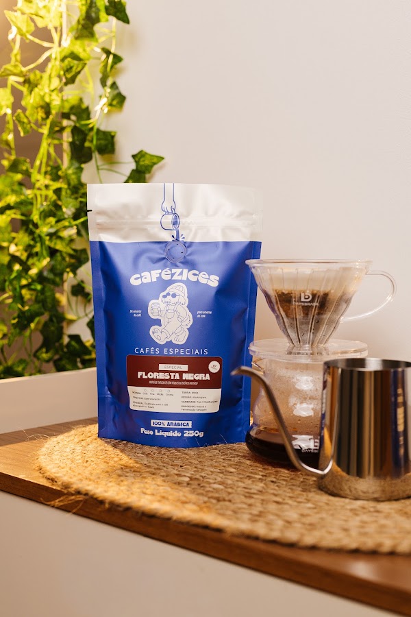 Pacote do caf&eacute; especial Floresta Negra ao lado de V60 com jarra, sobre cesto de palha